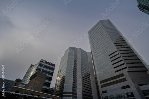 Low angle view of glass high rise office buildings in the central business district, showing a North American skyline, modern architecture and winter conditions under a cloudy sky.