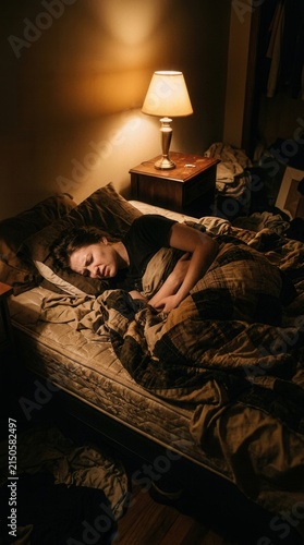 Woman Sleeping In A Dark Bedroom With Lamp Light