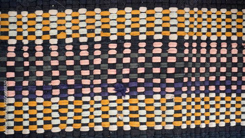 Traditional handmade woven fabric with colorful orange, pink and dark checkered pattern.