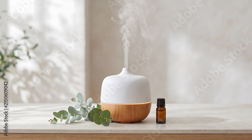 Wooden essential oil diffuser releasing mist beside eucalyptus leaves and an oil bottle on a light wooden table