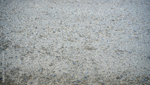 Rough gray concrete ground texture with scattered pebbles.