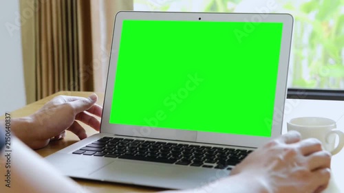 Person Using Laptop with Green Screen Display at Home
