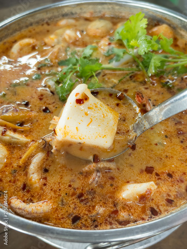 Foto Appetizing creamy Tom Yum seafood soup with fresh shrimp, squid, chili, mushrooms, and aromatic Thai herbs