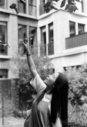 Canvas Print Young woman reaching for leaves in urban garden