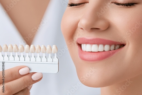 Woman comparing teeth shade with guide medical consultation