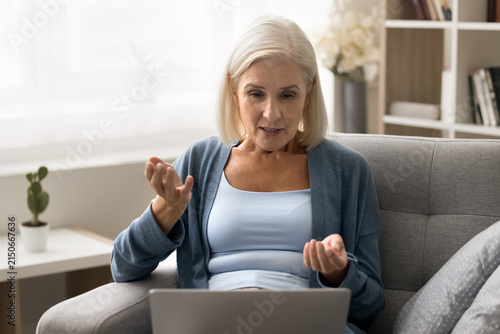 фотографія Older age woman retiree speak by video call chat with friend using laptop web camera sitting on cozy couch
