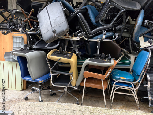 Stack of old broken office chairs stored outdoors