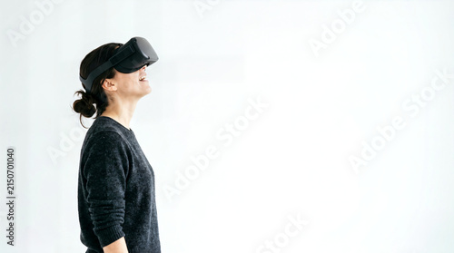 Woman wearing virtual reality headset looking up against a white background