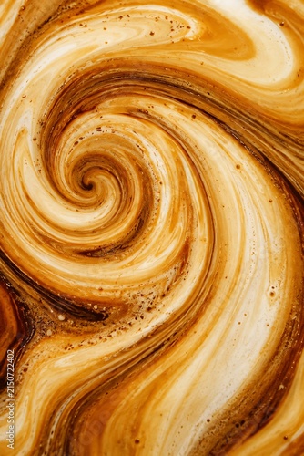 Top down view of swirling milk and espresso creating a hypnotic spiral