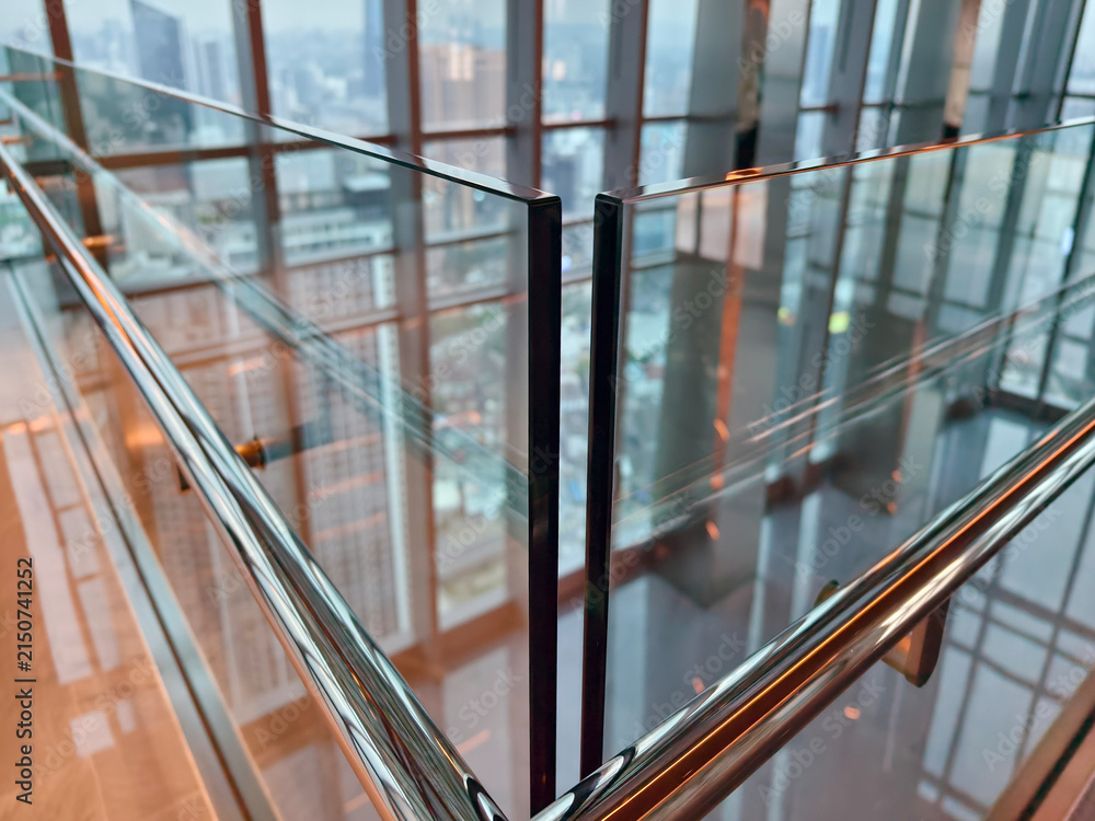 Fototapeta premium Spacious glass atrium with reflections on polished floor and panoramic windows. Empty lobby features