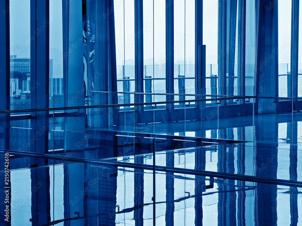 Fototapeta premium Spacious glass atrium with reflections on polished floor and panoramic windows. Empty lobby features