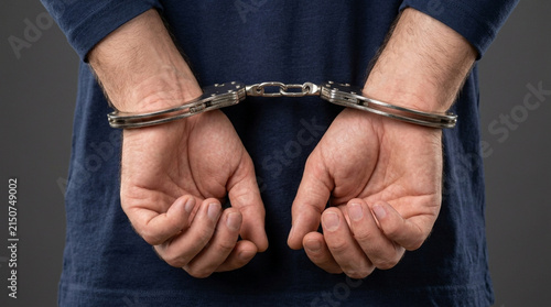 Man's hands cuffed behind back, legal justice concept