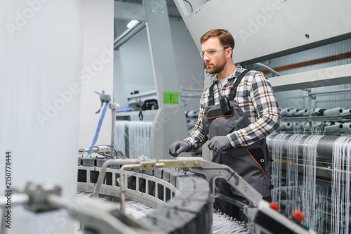 Fotografie Worker monitoring polypropylene yarn production process on textile machine