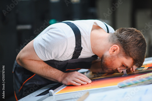 Obraz w ramie Printer worker checking printing quality using magnifying glass