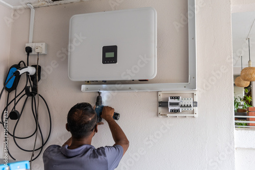 Technician installing solar photovoltaic hybrid inverter into a residential house