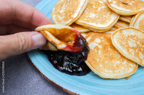 Hand Dipping Fluffy Mini Pancake into Dark Berry Jam