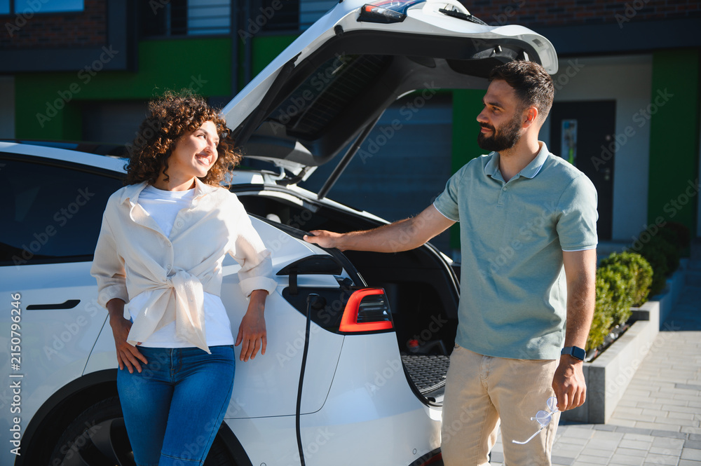 Fototapeta premium Couple charging electric car at home, embracing green energy and sustainable lifestyle