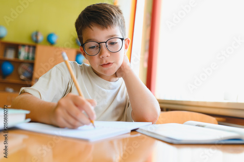 Fotografía Elementary school student writing in notebook at desk