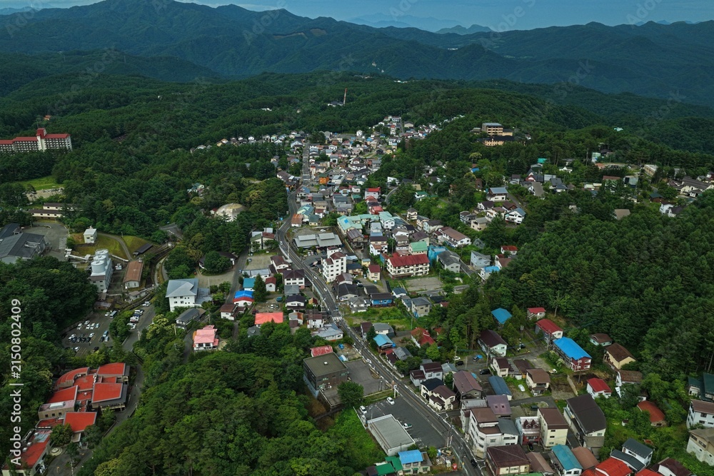Fototapeta premium Aerial drone photo of residential area and mountain landscape in Kusatsu, Gunma, Japan