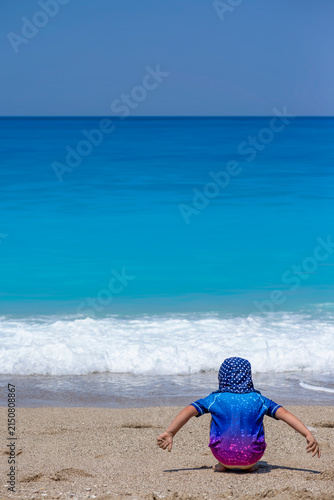 girl palying on the beach wearing sun protective clothes