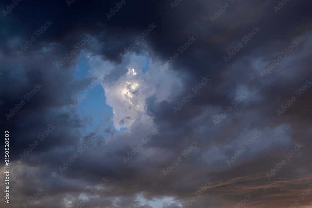 Obraz premium Dramatic storm clouds with blue sky and sunlight breaking through
