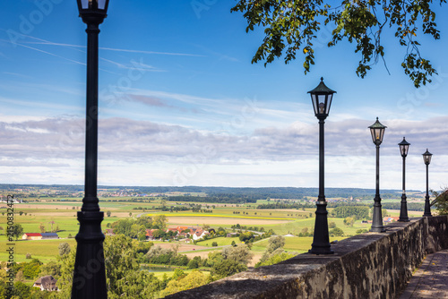 Charming rural landscape with traditional street lamps on a sunny day, showcasing expansive fields and distant villages. Region of Bavaria in Germany, Europe.