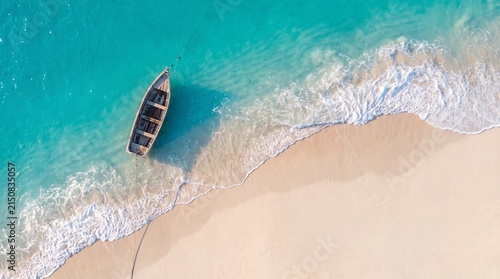 Aerial view of a small wooden rowboat anchored on a pristine tropical beach shoreline.