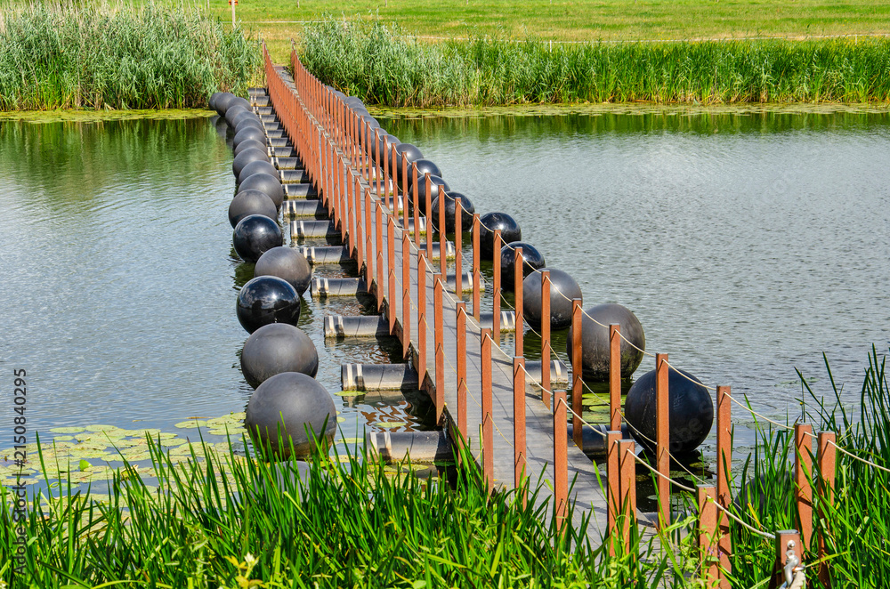 Obraz premium Den Nul, The Netherlands, July 20, 2026: view from the southeast towards the innovative floating pedestrian bridge across the Lange Kolk river channel