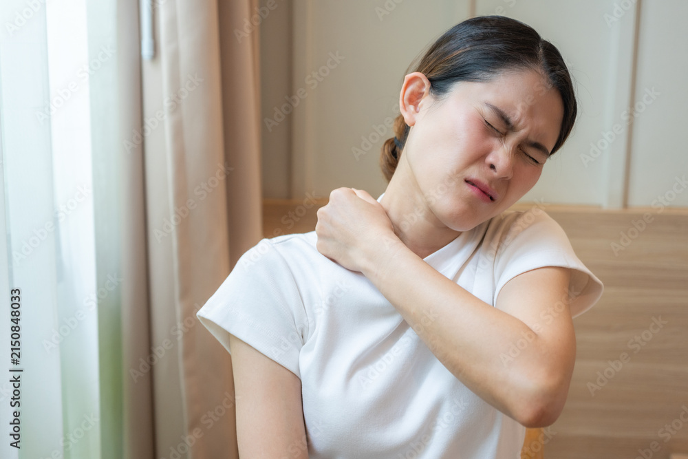 Naklejka premium Asian woman having shoulder and neck pain from working longtime. Shoulder pain is when rotator cuff tendons become inflamed or trapped in your shoulder.