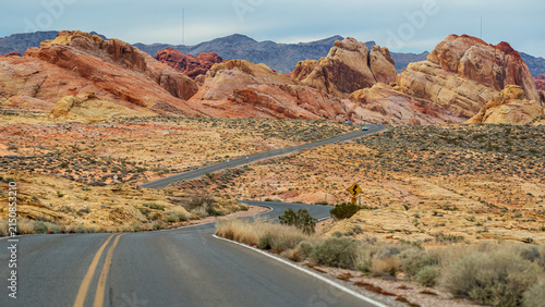 Winding desert road through red and yellow sandstone formations in Valley of Fire State Park, Nevada.