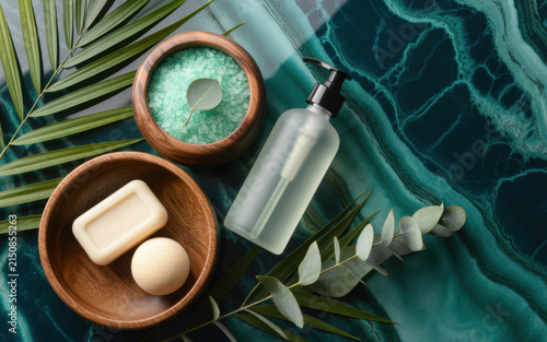 Spa and wellness flat lay with natural soap, bath salts, and eucalyptus leaves on a dark green marble surface for relaxation and self-care concepts and beauty treatments