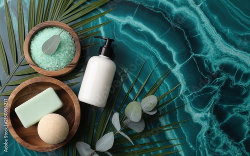 Spa treatment flat lay featuring natural soap bar, bath salts in wooden bowl, and eucalyptus sprigs on a dark green marble background, for holistic wellness, and skincare