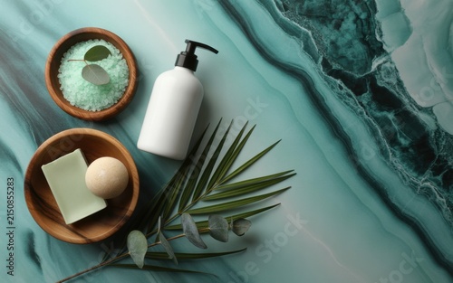 Spa wellness composition with white lotion bottle, sea salt in wooden bowl, natural soap bar, and eucalyptus leaves on a textured green marble background, luxury care