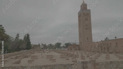 Handheld horizontal pan right revealing Koutoubia Mosque minaret tower through palm trees Marrakech