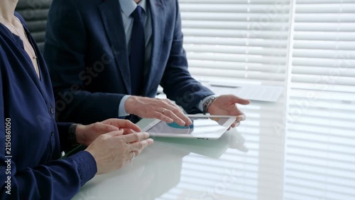 Business colleagues reviewing financial reports and analytics on a touchscreen tablet during a corporate meeting, collaborating on strategy and discussing growth opportunities