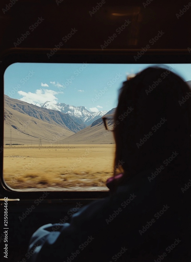 Obraz premium Passenger Silhouette Looking Through Train Window at Snow Capped Mountains and Valley Landscape