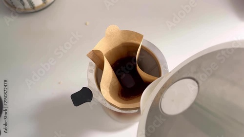 Brewing coffee with paper filter in a pour-over coffee maker on a clean countertop