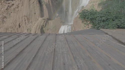 Real time tilt up shot from emerald basin pool to thundering Ouzoud Waterfalls peak