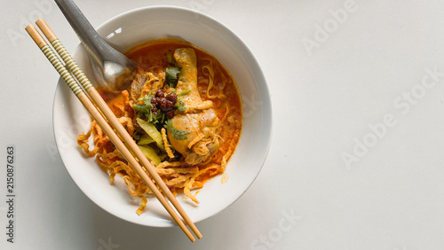 Traditional Northern Thai chicken khao soi curry noodle soup served with tender chicken, crispy noodles, pickled mustard greens, fresh herbs, and rich aromatic coconut curry broth in a white bowl.