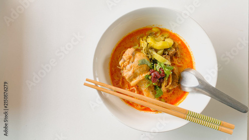 Traditional Northern Thai chicken khao soi curry noodle soup served with tender chicken, crispy noodles, pickled mustard greens, fresh herbs, and rich aromatic coconut curry broth in a white bowl.