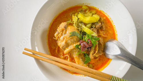 Traditional Northern Thai chicken khao soi curry noodle soup served with tender chicken, crispy noodles, pickled mustard greens, fresh herbs, and rich aromatic coconut curry broth in a white bowl.