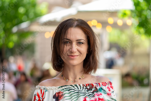 Bild auf Leinwand Smiling brunette woman with windblown hair posing outdoors in summer cafe