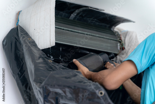 A professional HVAC technician cleans and services an indoor air conditioner unit in a residential house.