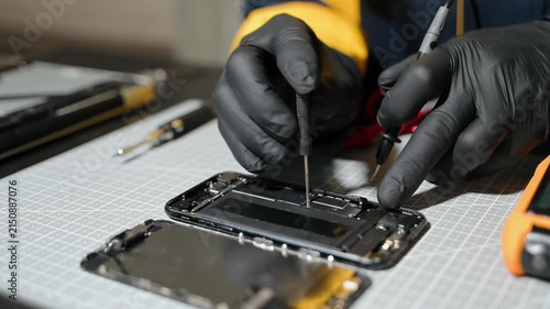 Professional technician repairing a smartphone using a multimeter for circuit diagnostics in an electronics workshop. Ideal for technology, repair service, and engineering