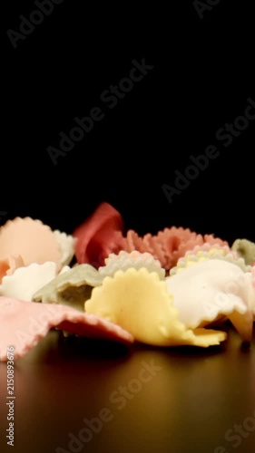 MACRO: Raw colour figural pasta fall on a black table, Slow motion