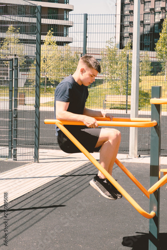 Quadro su tela Young Man Exercising on Parallel Bars at Outdoor Street Workout Gym in Summer