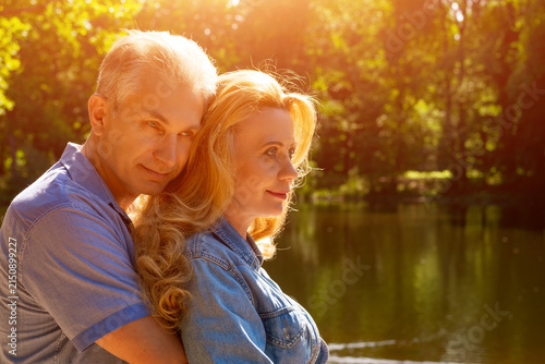 Canvas Print Mature Man Embracing a Woman Cheek to Cheek in a Park