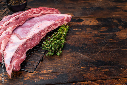 Fotografía Raw Uncooked lamb ribs breast cut on metal rack with thyme and peppercorns dark