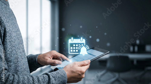 Close up of a person using a tablet with calendar and notification icons floating above, symbolizing event planning and reminders