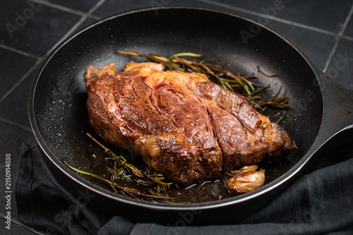 Fried beef chuckeye steak with caramelized crust fried in pan. Restaurant style beef meat on dark tile surface.